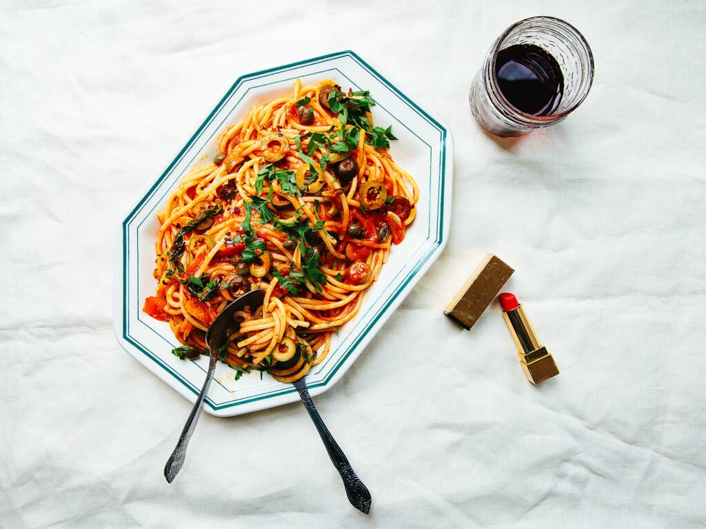 plate of pasta puttanesca and a glass of red wine