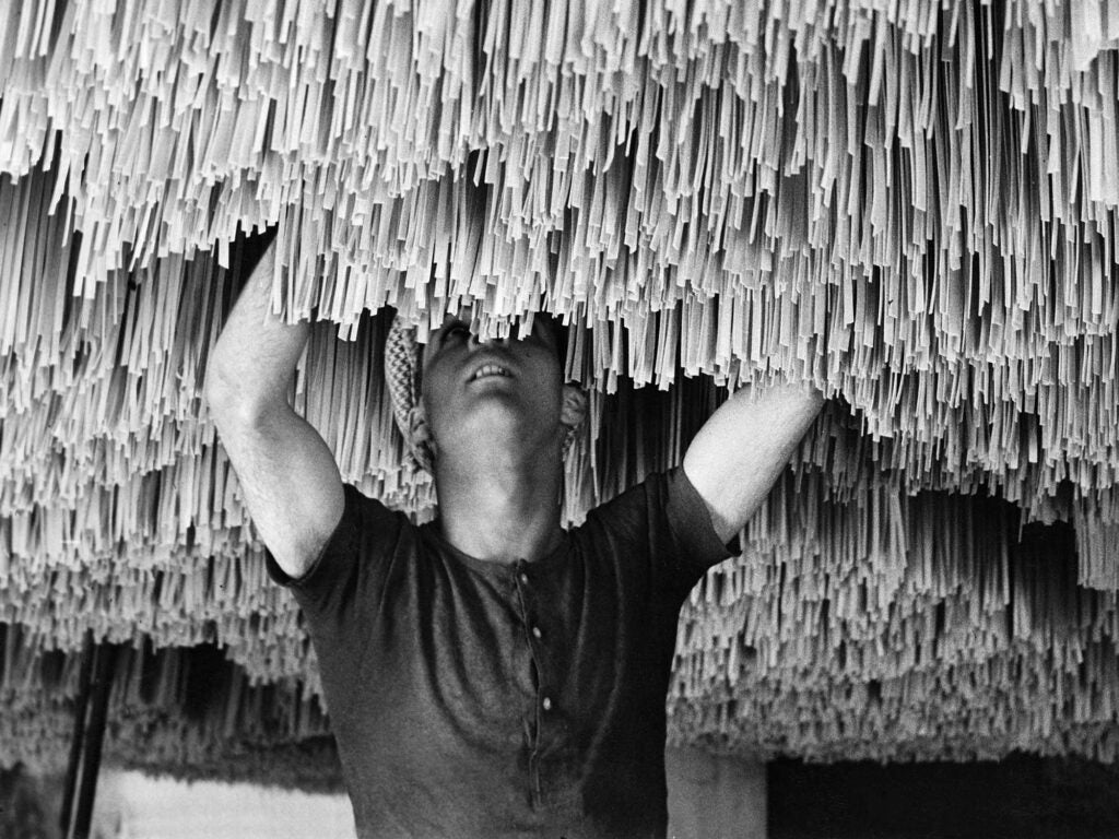 A worker hangs spaghetti to dry in 1930s Italy.