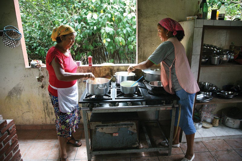 Women prepare a meal in their open-air kitchen.