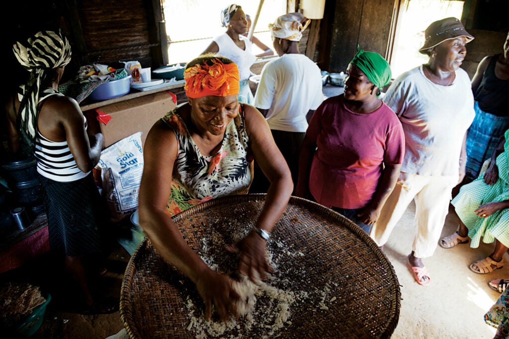 Camilla Leslie Crisanto Avila sifts cassava to make flour for bread while other Garifuna women look on