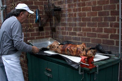 a man carves the Easter lamb in the backyard of their house in Queens, New York
