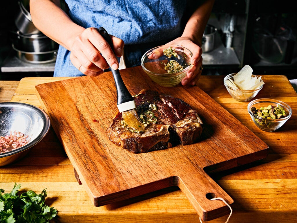 seasoning cooked steak on wooden cutting board