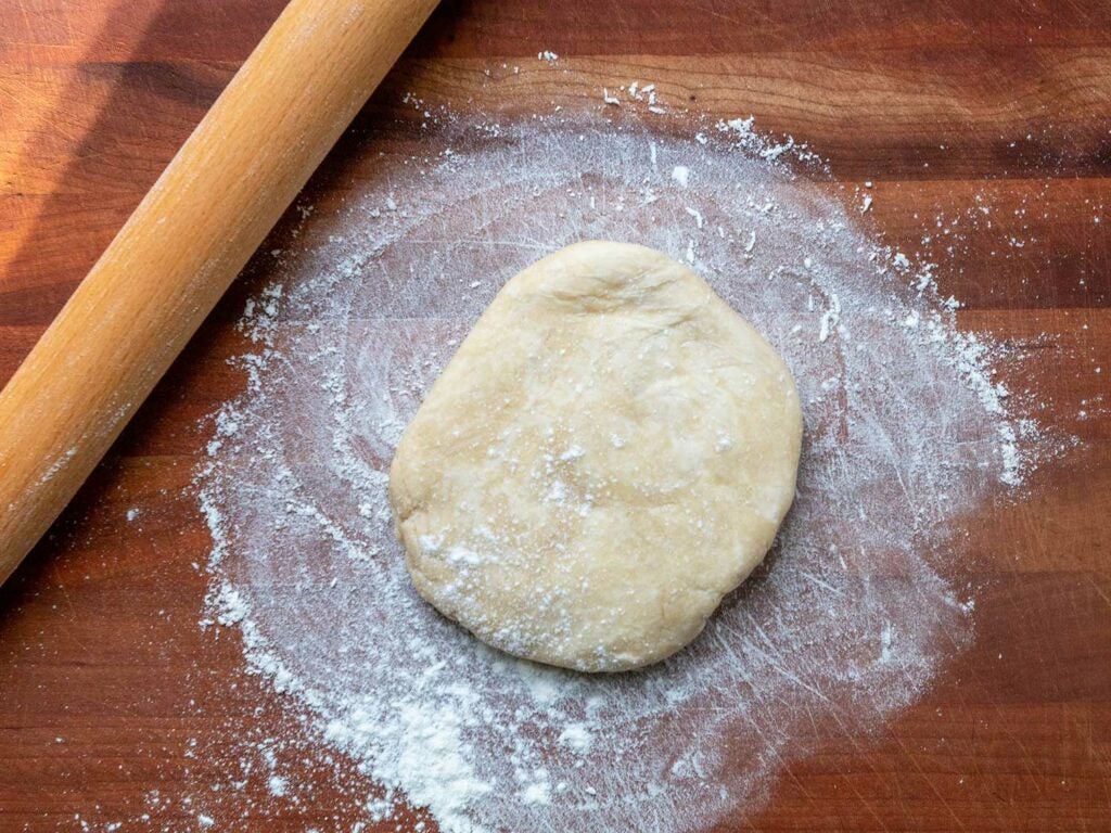 Floured pie dough and rolling pin on countertop.