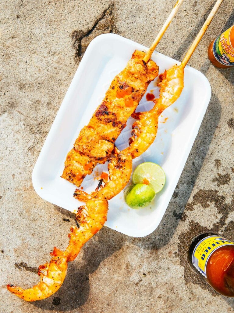 A plate of fish and shrimp skewers served with limes and Salsa Huichol.