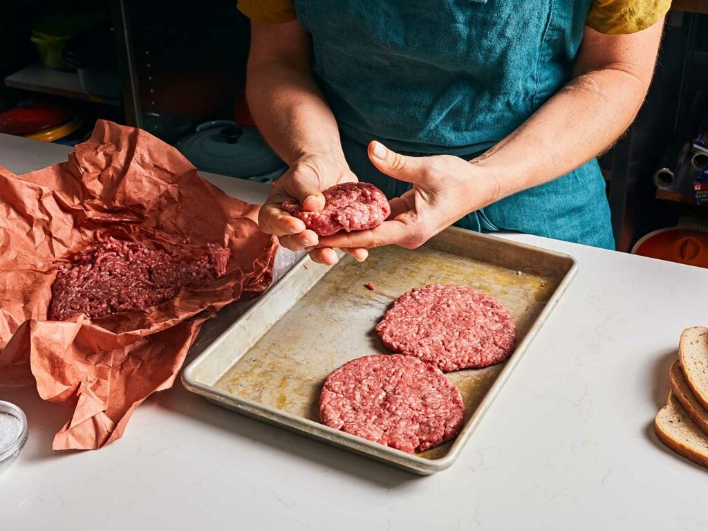 Hand-patting patties and placing on baking sheet.