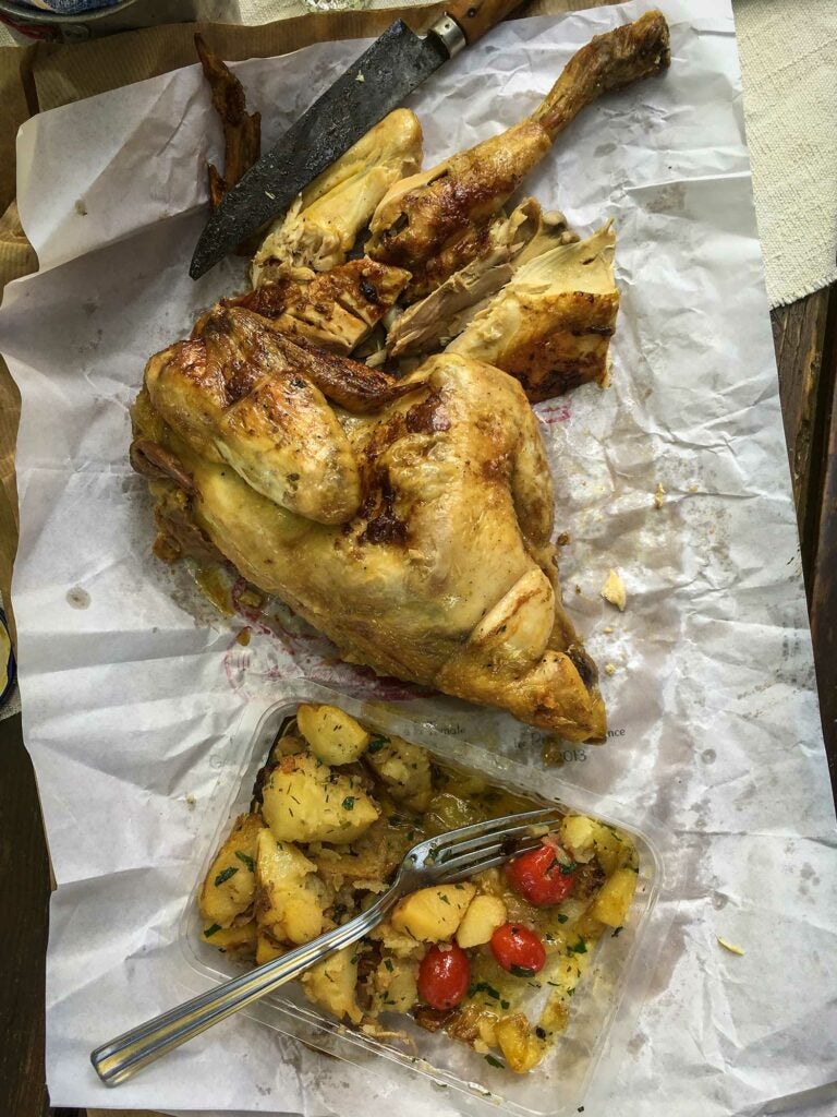 A store-bought rotisserie chicken laid out at a picnic.