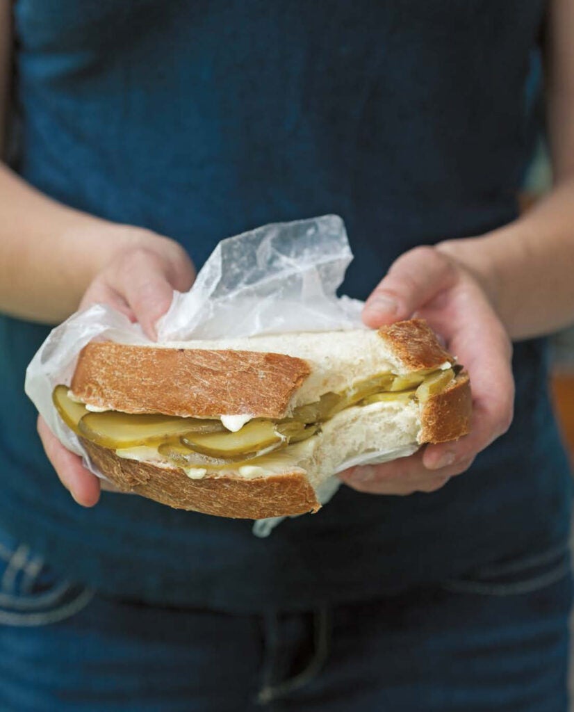 Person holding a bread-and-butter pickle sandwich