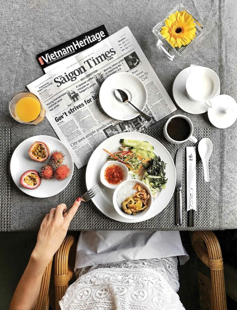 Woman having a meal and reading the Saigon Times